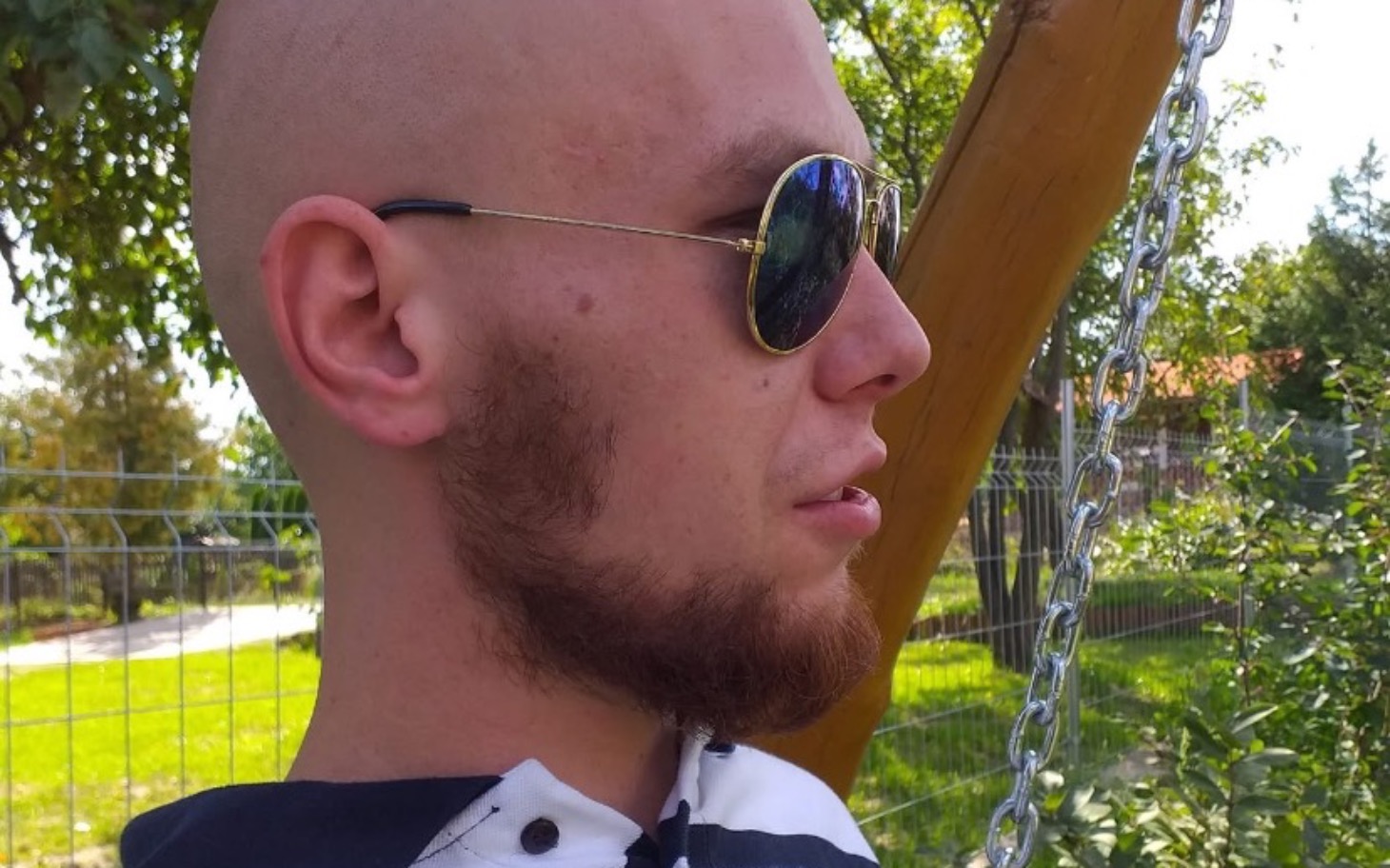 
        Mężczyzna w okularach przeciwsłonecznych, siedzący na huśtawce.
    