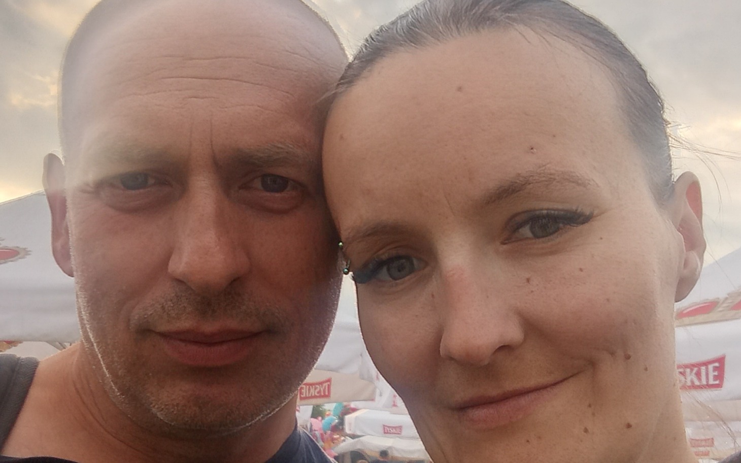 
        Para pozująca do zdjęcia na festiwalu, uśmiechnięta i zadowolona.
    