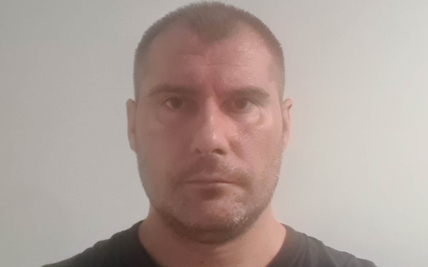 
        Mężczyzna z poważnym wyrazem twarzy, patrzący w obiektyw.
    