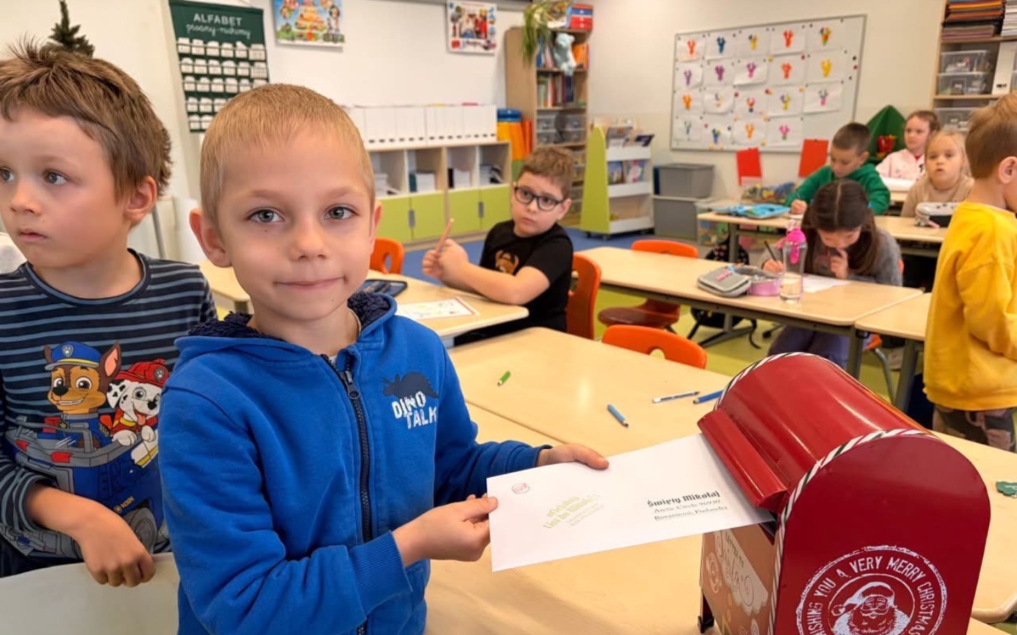 
        Chłopiec wrzucający list do skrzynki w klasie.
    