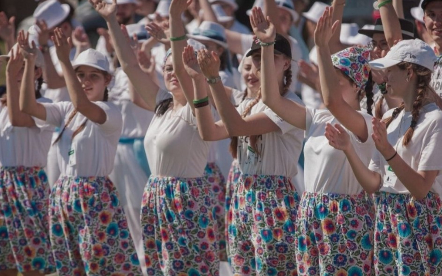 
        Grupa dziewcząt w kolorowych spódnicach tańczących razem.
    