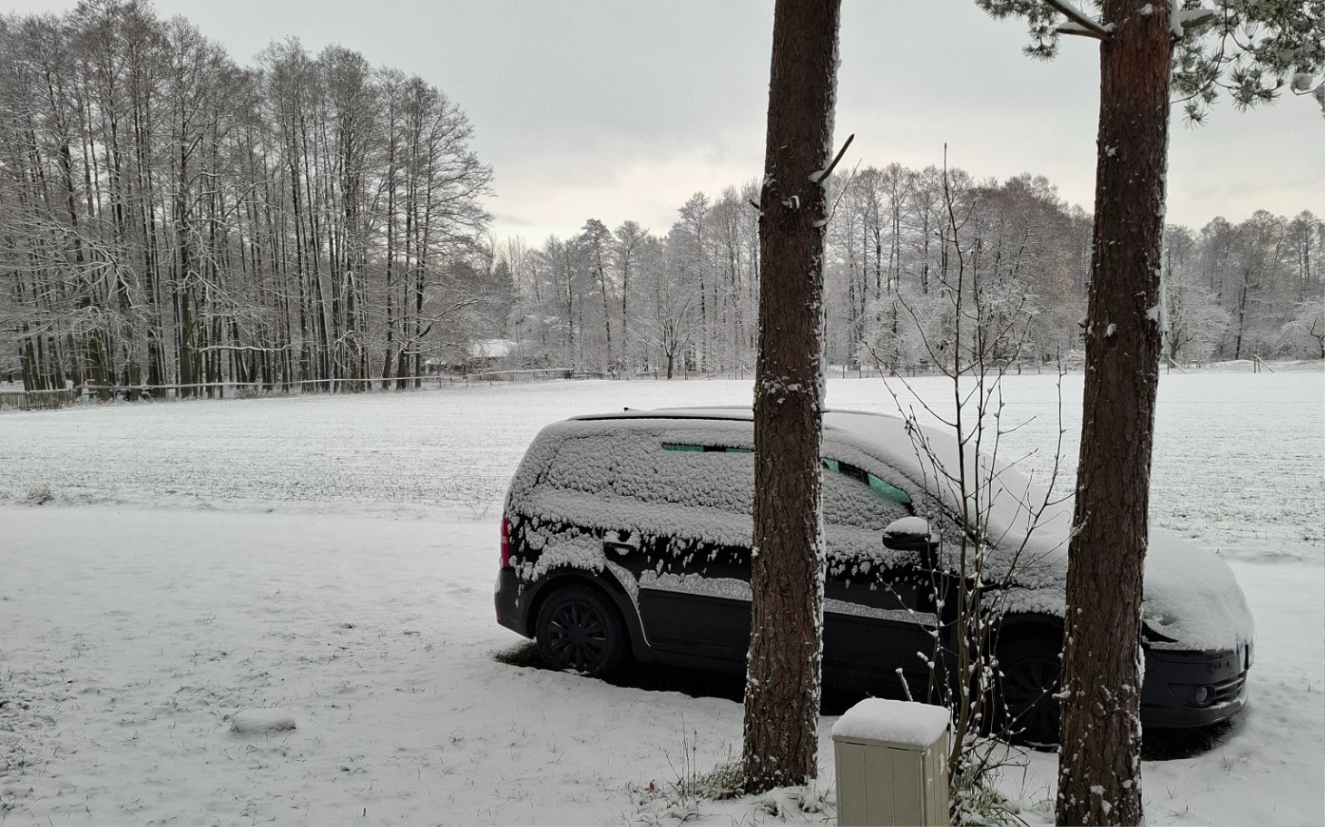 
        Samochód pokryty śniegiem w zimowym krajobrazie.
    
