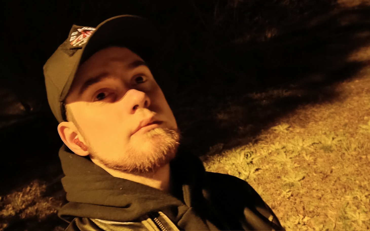 
        Mężczyzna w czapce, selfie w nocy, z tłem przyrody.
    