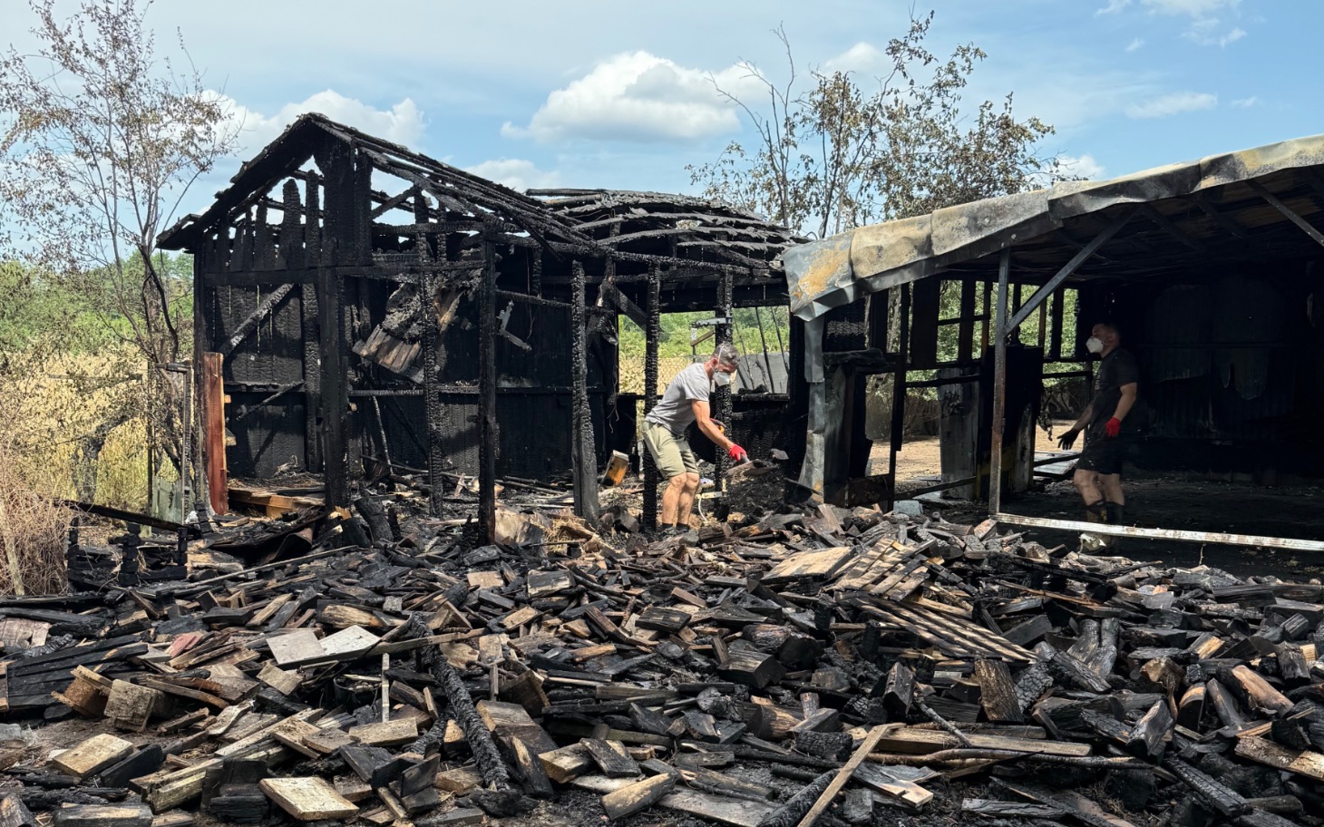 
        Zniszczony budynek po pożarze, w tle pracujący ludzie.
    