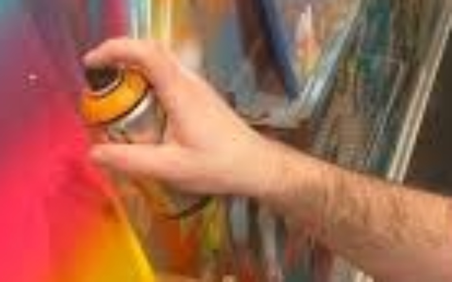 
        Artysta malujący graffiti na kolorowej ścianie.
    