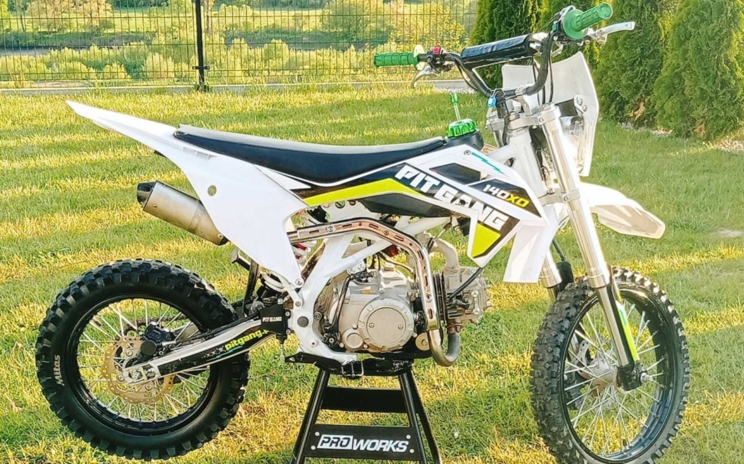 
        Motocykl pit bike na tle zielonego krajobrazu.
    