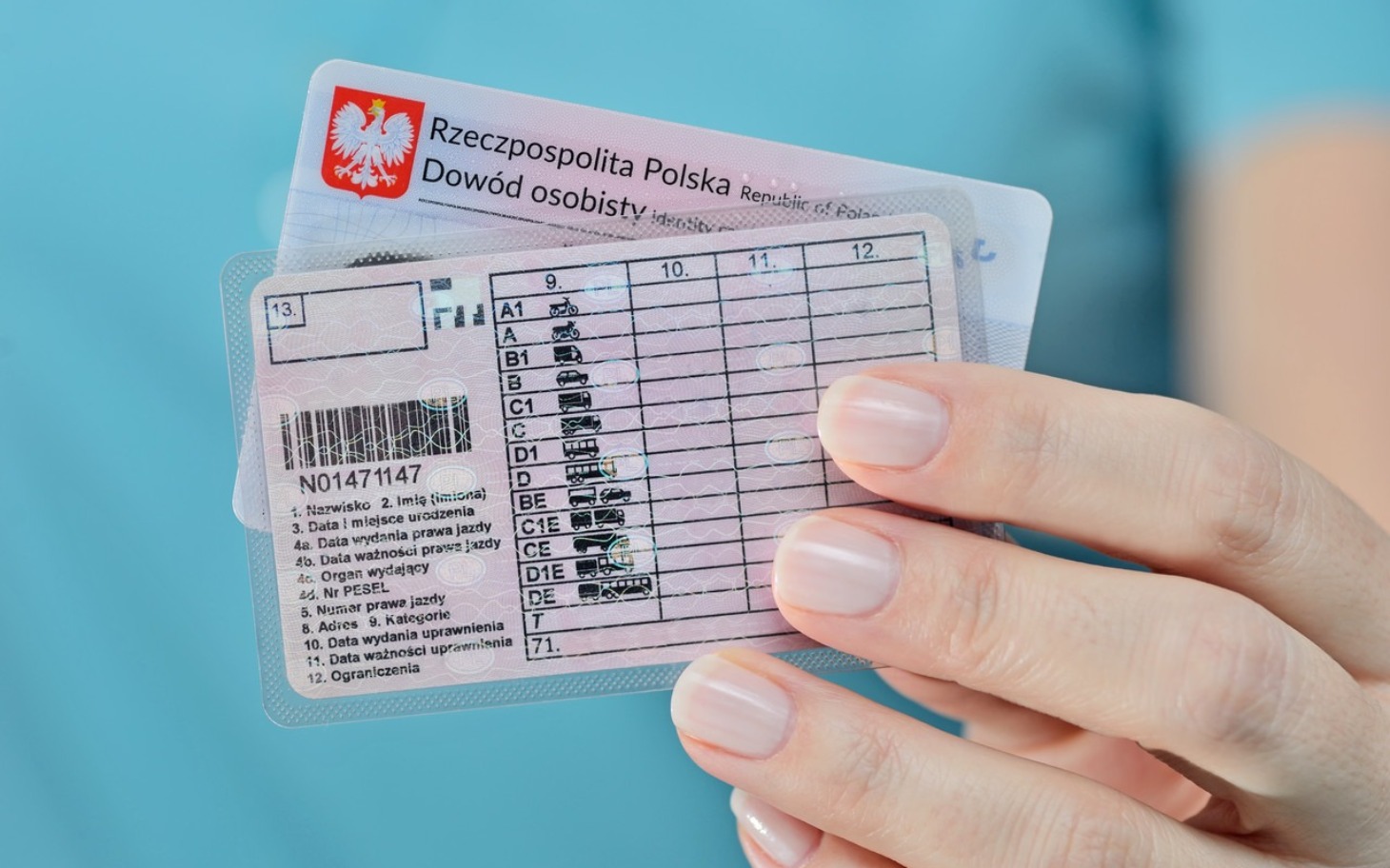 
        Osoba trzymająca dowód osobisty w dłoni.
    