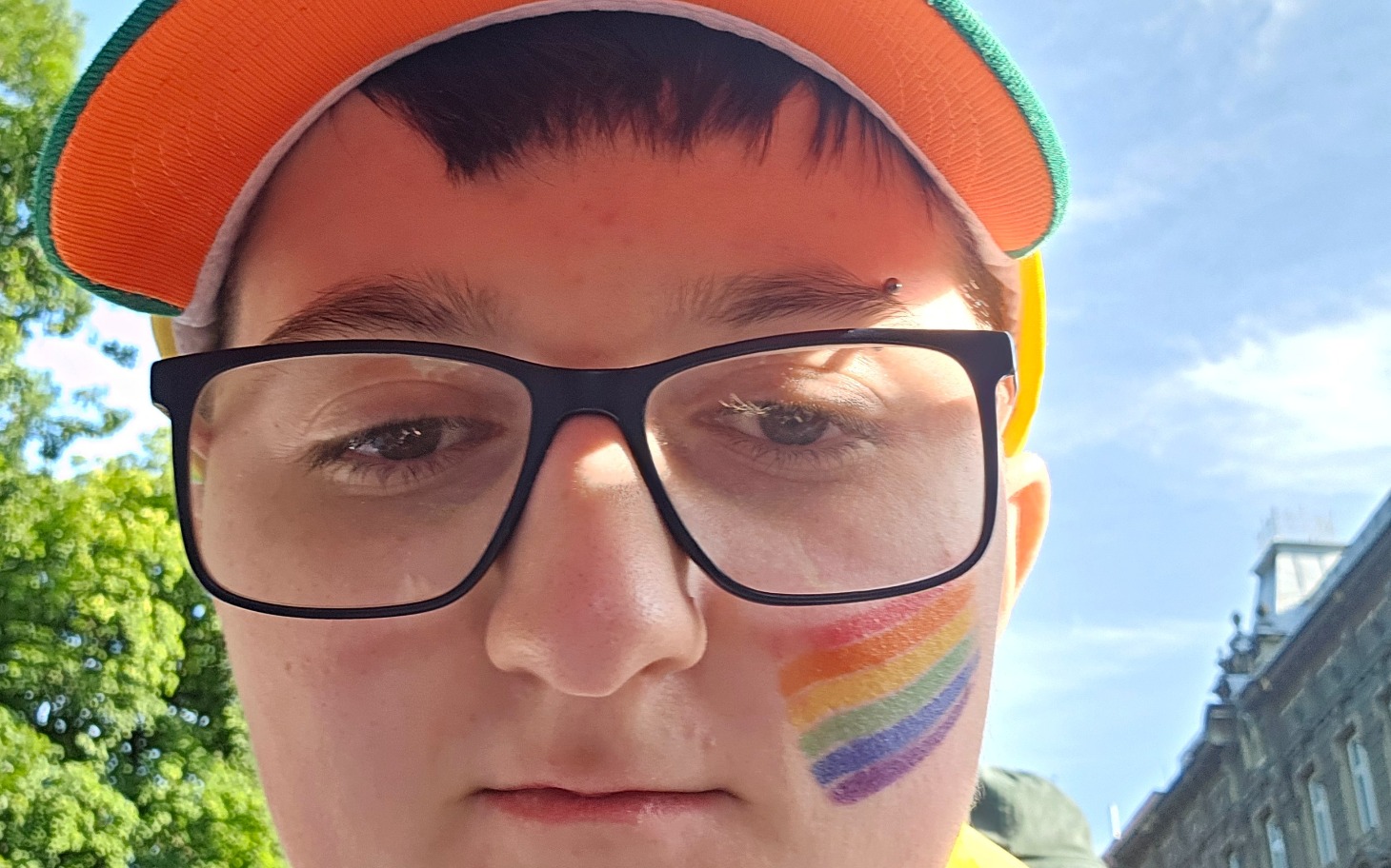 
        Młody człowiek z tęczowym malunkiem na policzku.
    