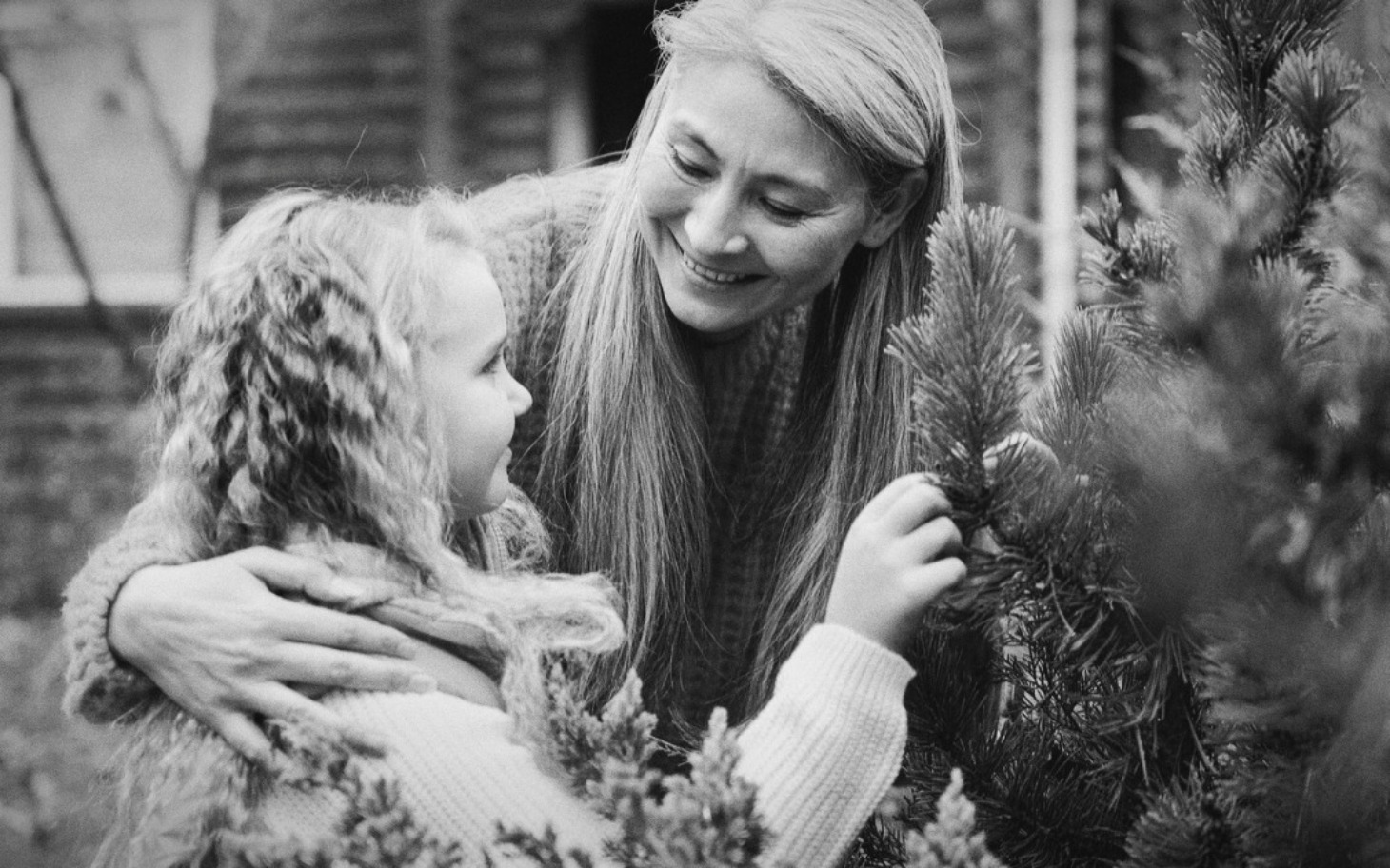 
        Matka i córka uśmiechają się do siebie w ogrodzie.
    