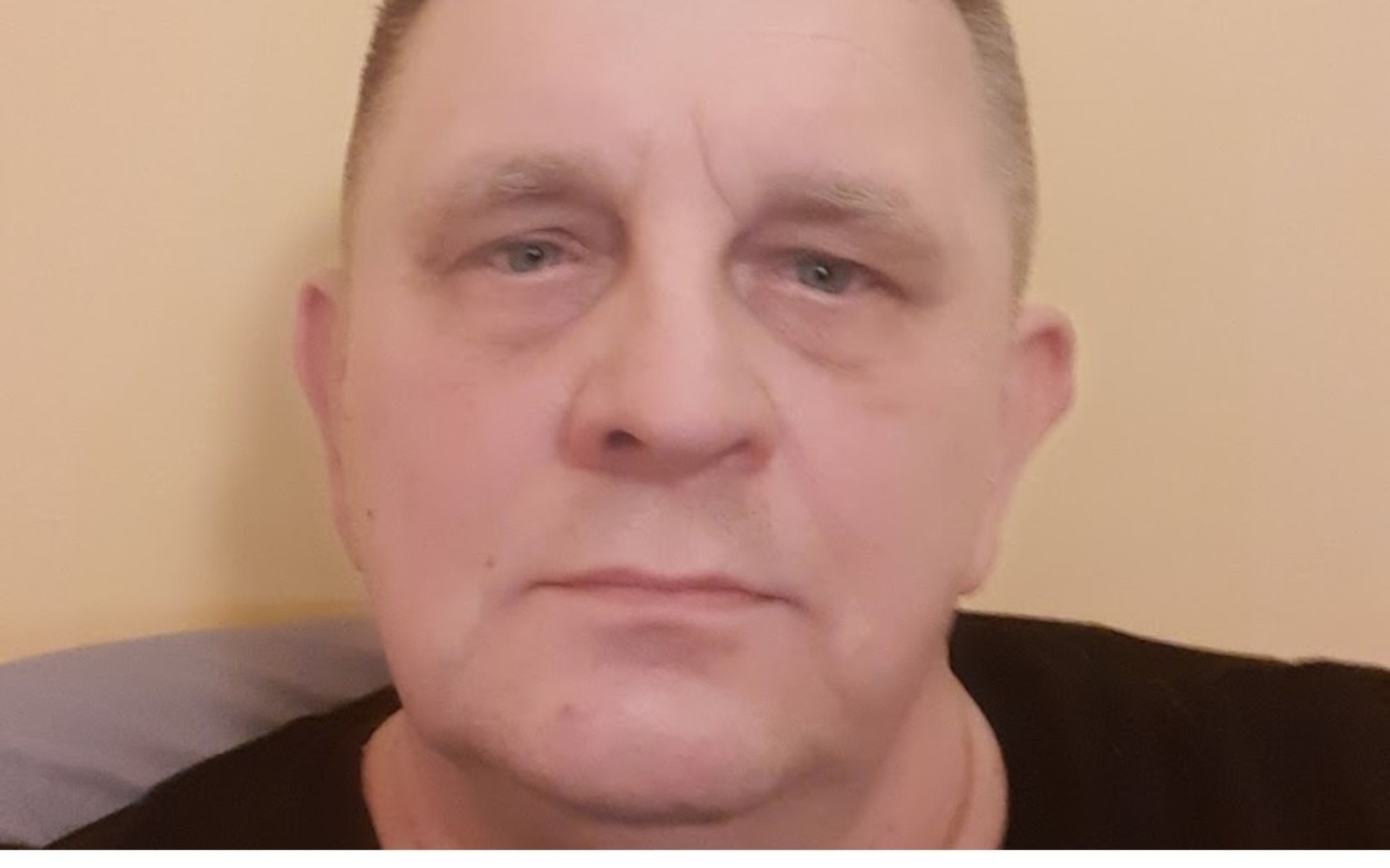 
        Mężczyzna z poważnym wyrazem twarzy, patrzący w kamerę.
    