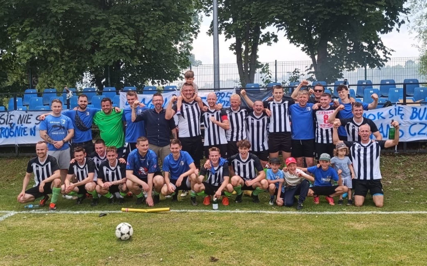 
        Grupa ludzi w strojach piłkarskich, świętujących zwycięstwo.
    