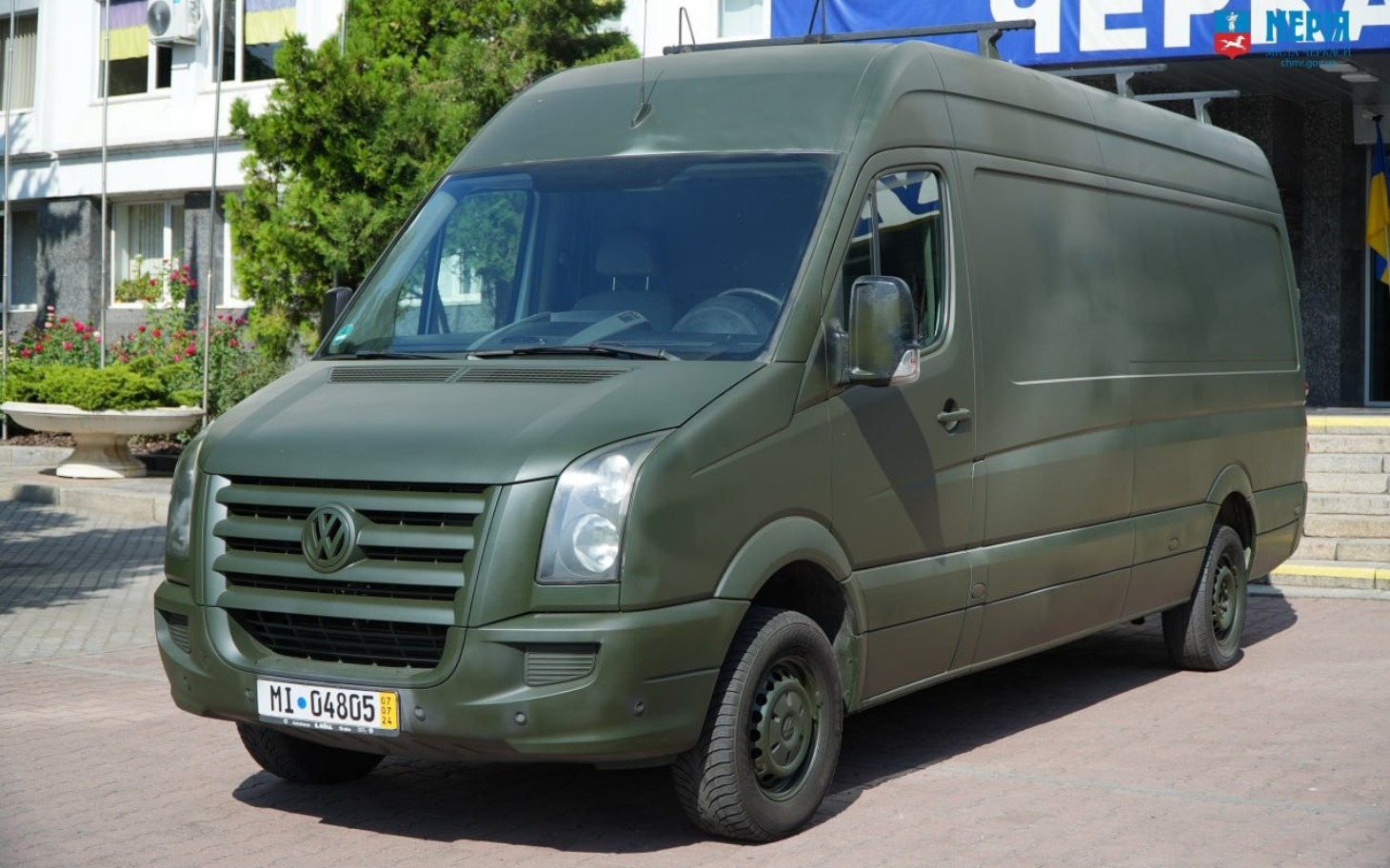 
        Zielony samochód dostawczy zaparkowany na chodniku.
    