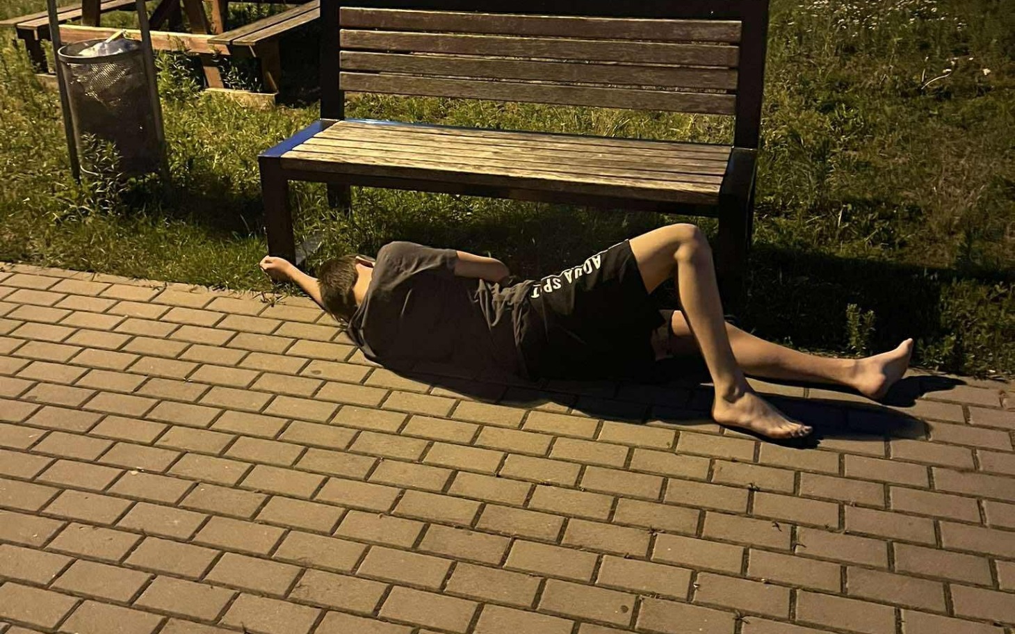 
        Osoba leżąca na chodniku, odpoczywająca w parku.
    