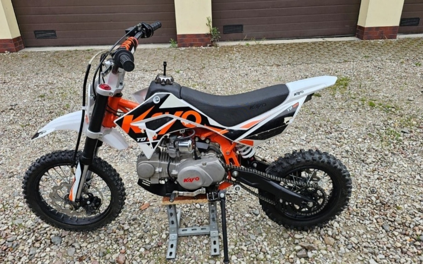 
        Motocykl dziecięcy na podjeździe, gotowy do jazdy.
    