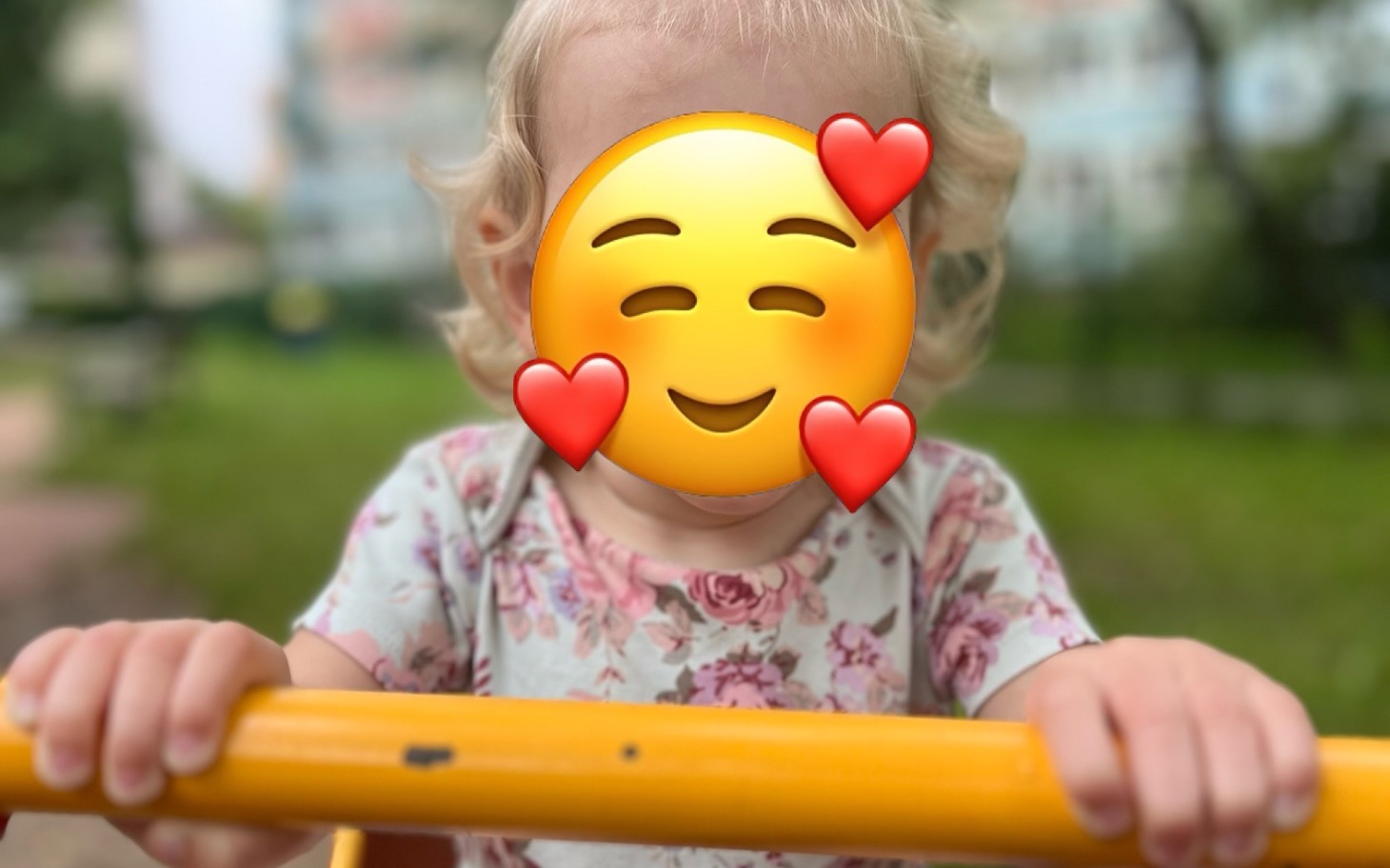 
        Dziecko na huśtawce z uśmiechem i serduszkami na twarzy.
    