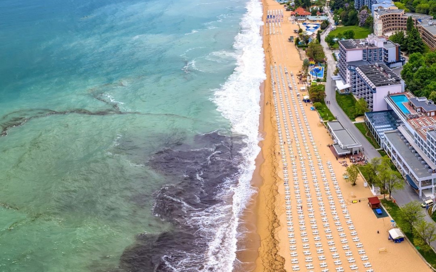 
        Widok na plażę z leżakami i morzem w tle.
    