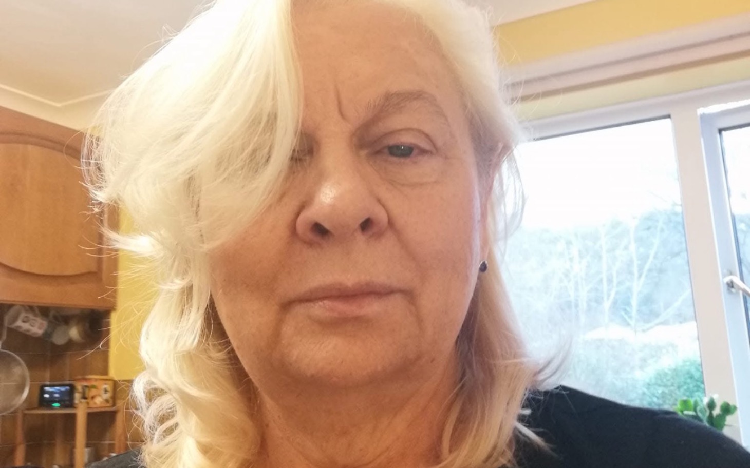 
        Starsza kobieta z naturalnym makijażem w kuchni.
    