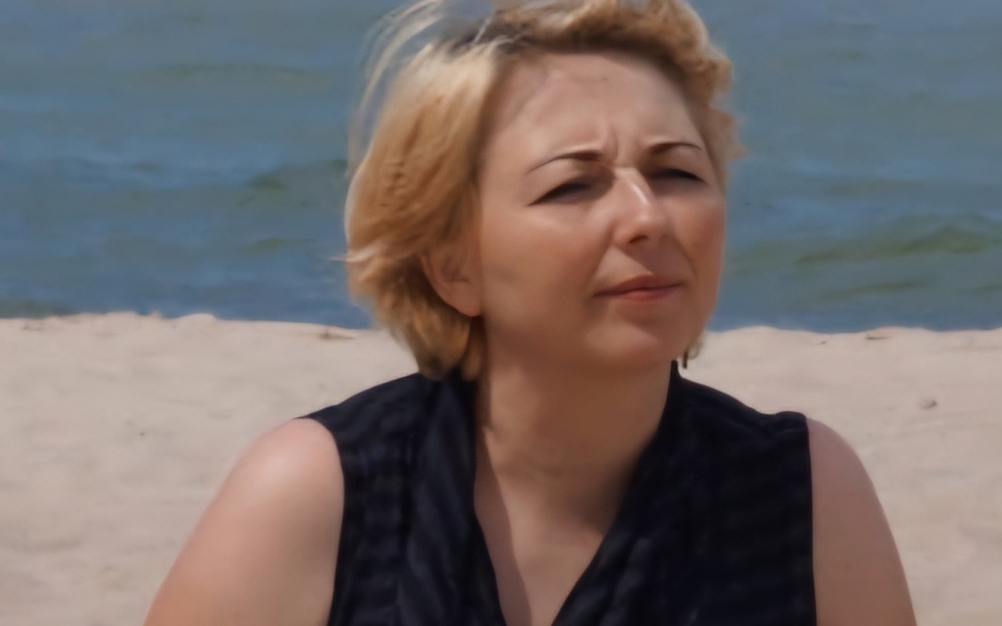 
        Kobieta na plaży, ciesząca się słońcem.
    