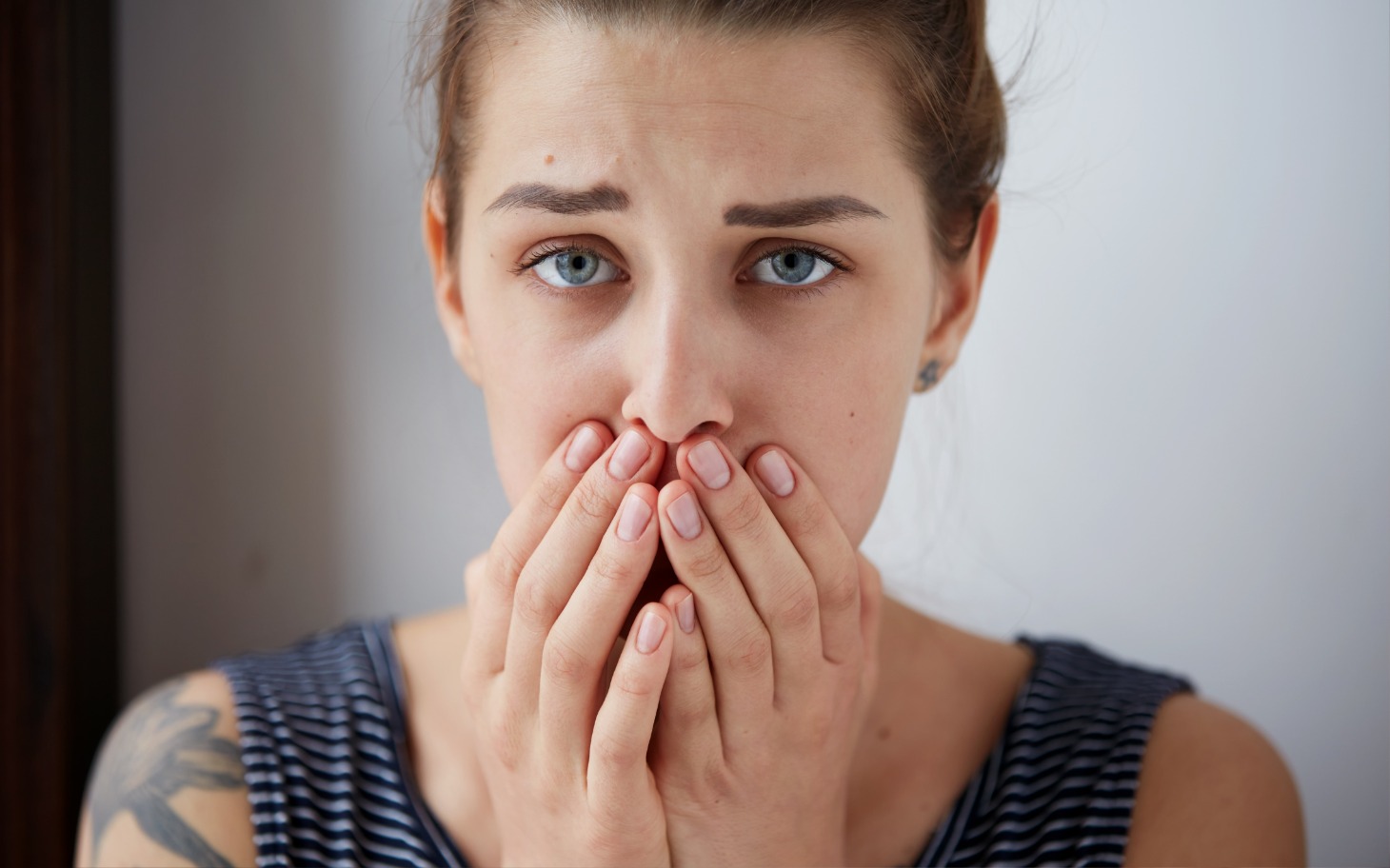 
        Młoda kobieta z zaniepokojonym wyrazem twarzy, zakrywająca usta.
    