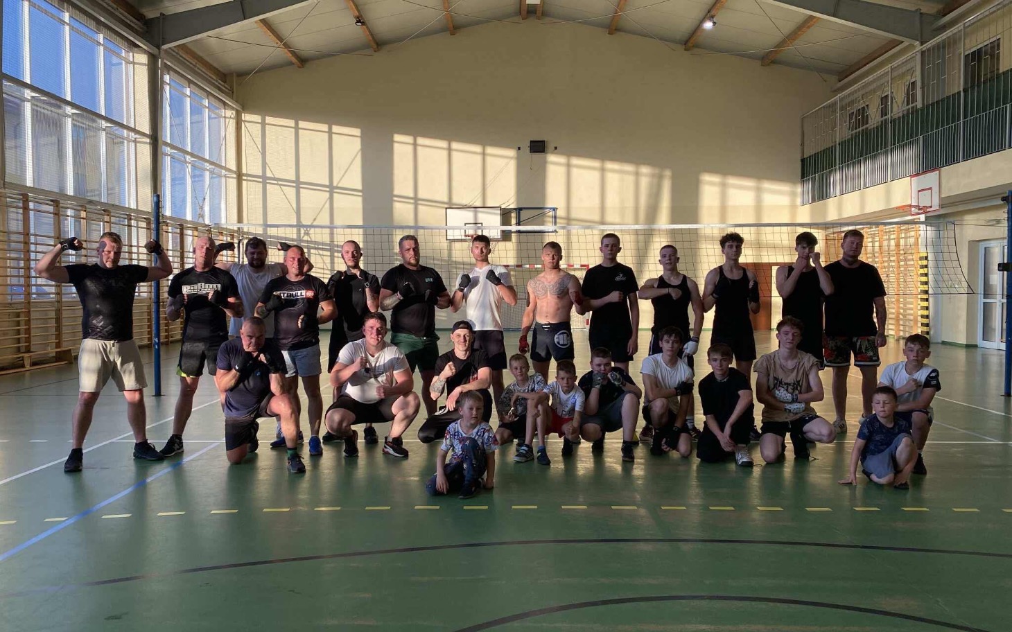 
        Grupa ludzi na treningu sportowym w hali.
    