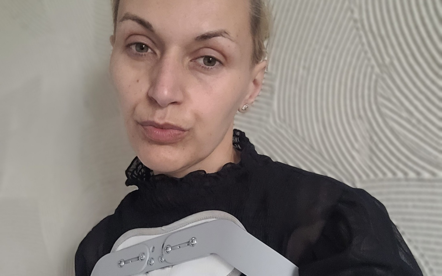 
        Kobieta trzymająca aparat ortopedyczny na ramieniu.
    