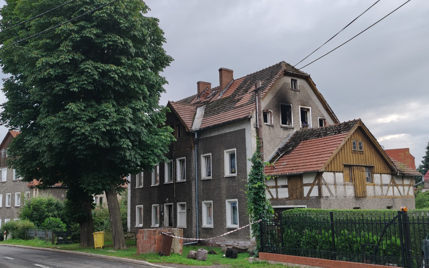 
        Zabytkowy dom z zielonym drzewem w tle.
    