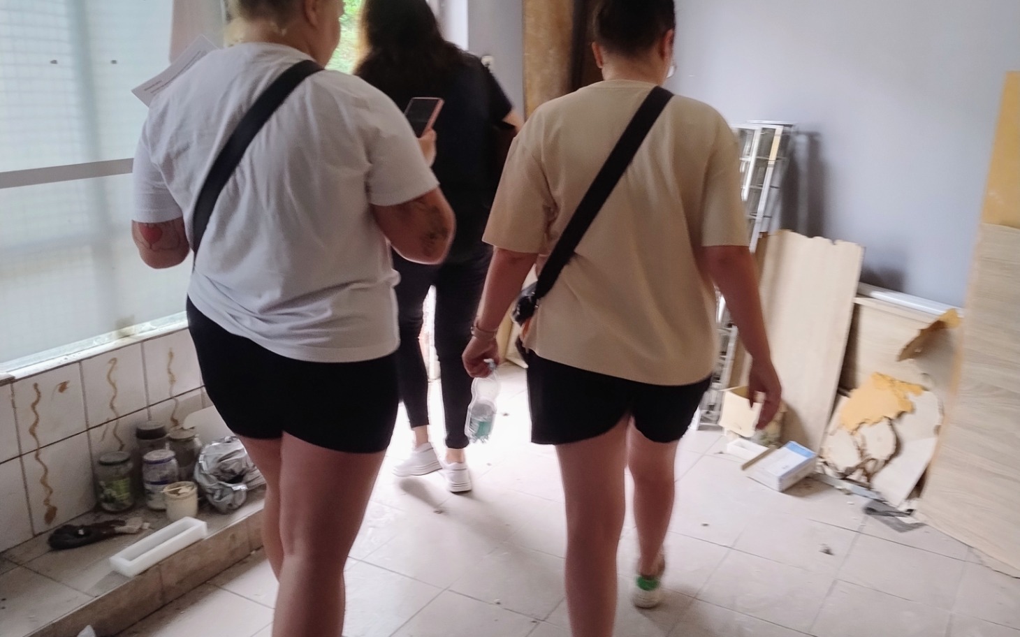 
        Dwie kobiety idące w stronę pomieszczenia, w tle widać remont.
    