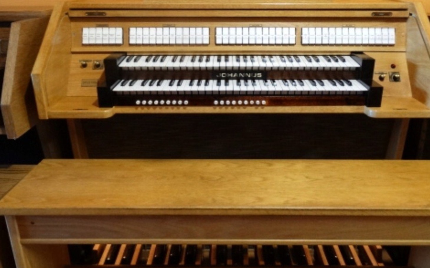 
        Stary organ z wieloma klawiszami i pedałami, w drewnianej obudowie.
    