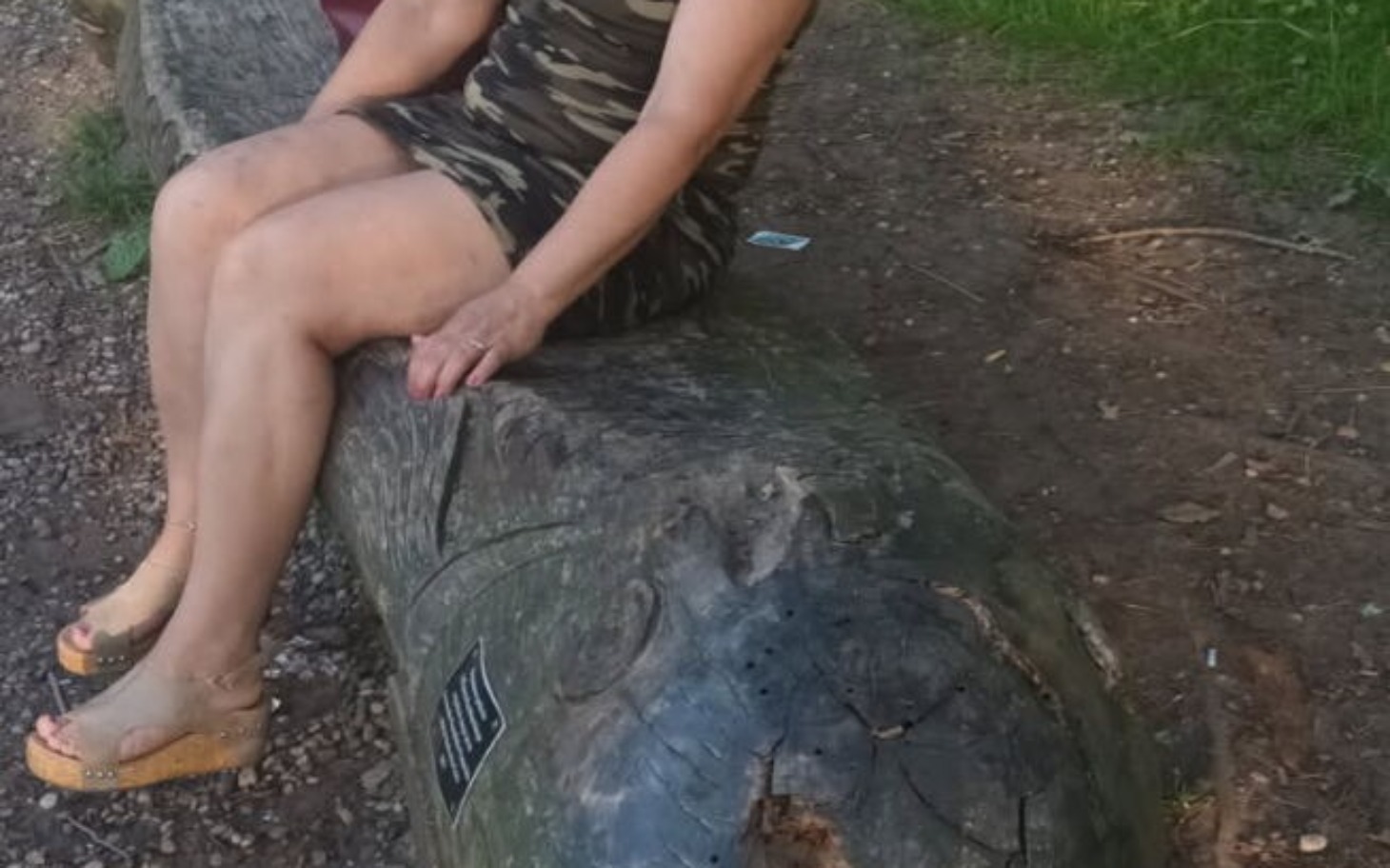 
        Kobieta siedząca na pniu drzewa w lesie.
    