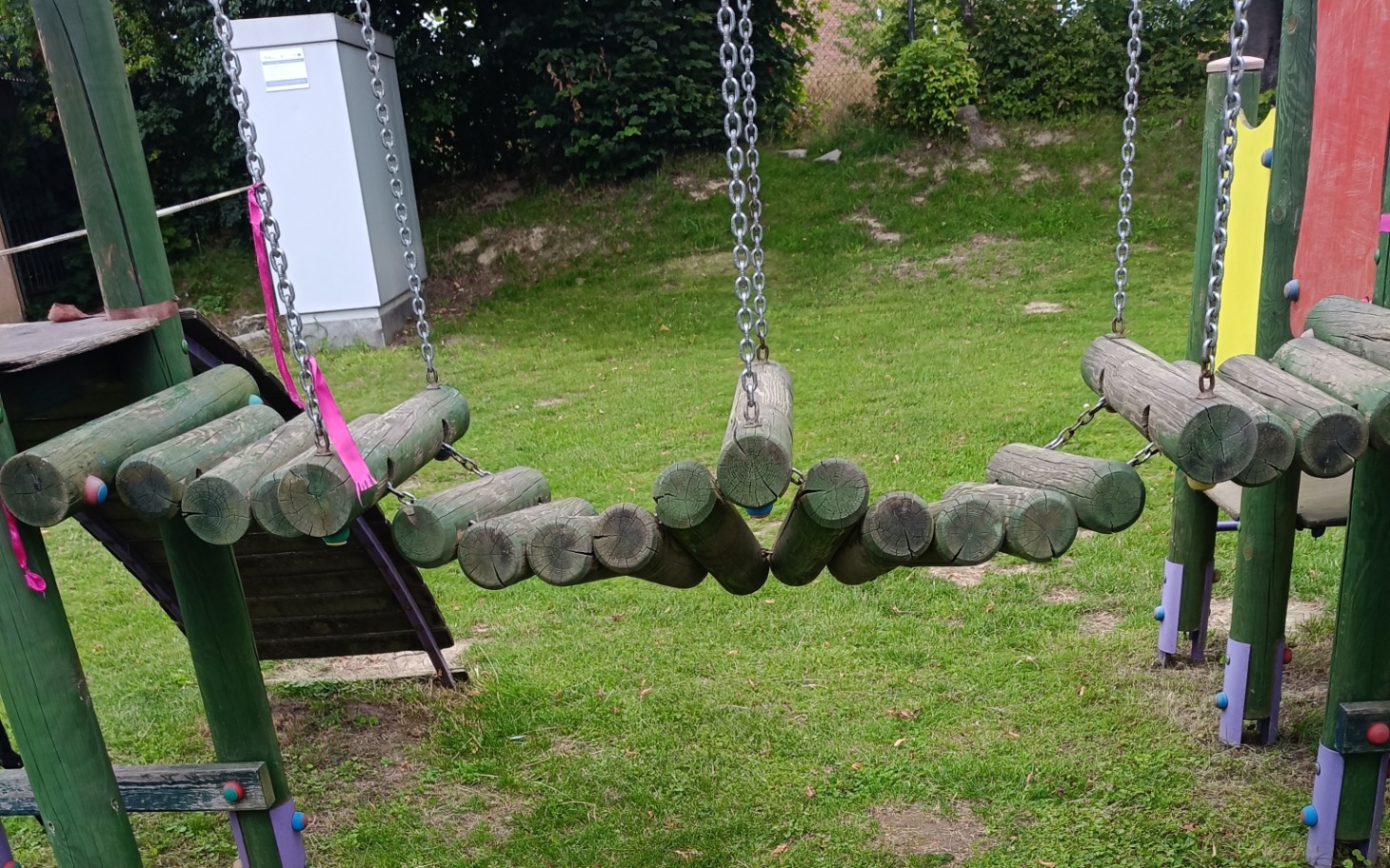 
        Huśtawki na placu zabaw w otoczeniu zieleni.
    