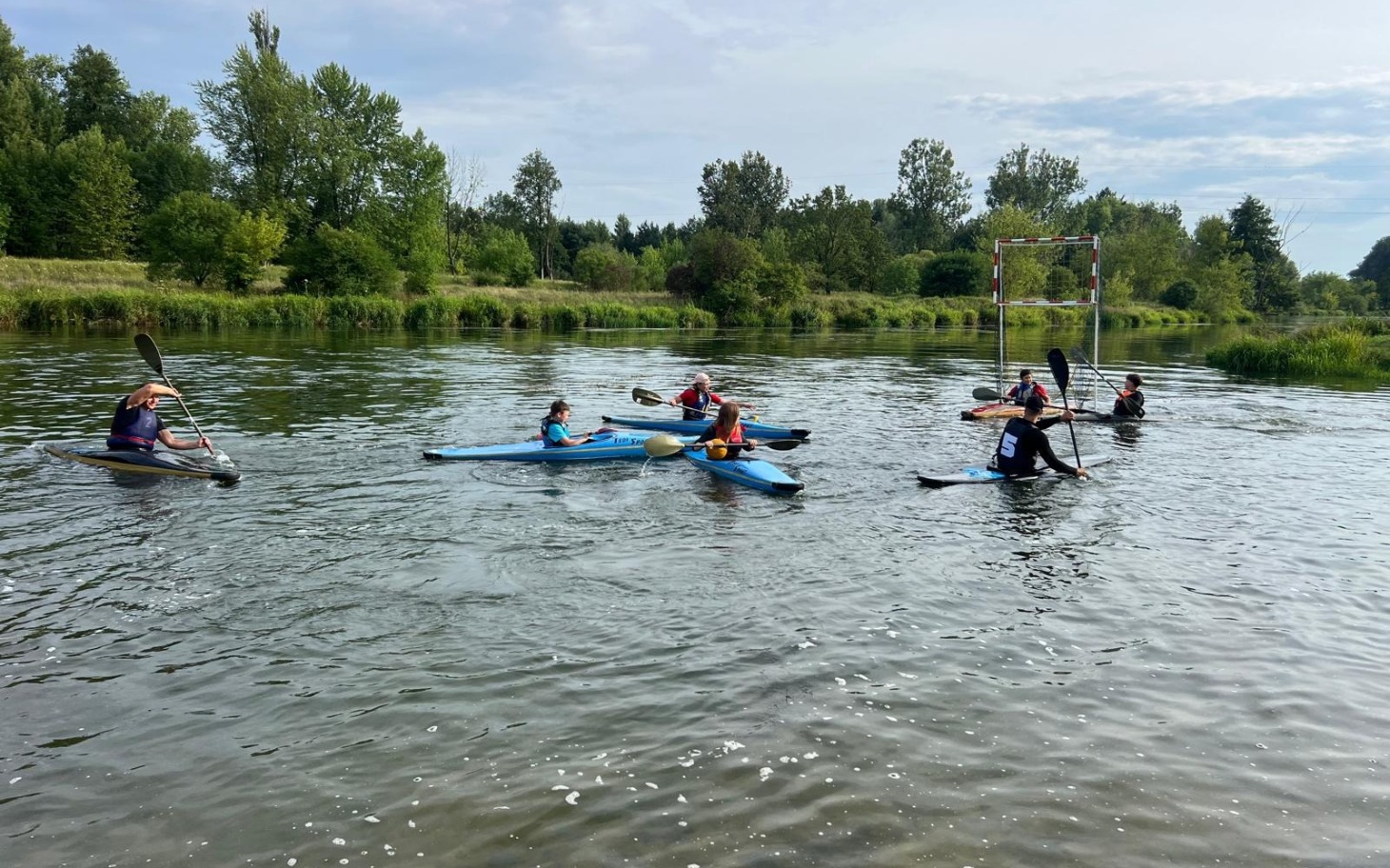 
        Grupa kajakarzy na rzece, cieszących się aktywnym wypoczynkiem.
    