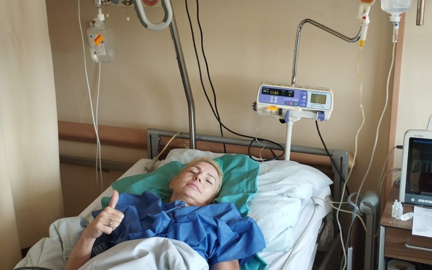 
        Kobieta w łóżku szpitalnym, pokazująca kciuk w górę.
    