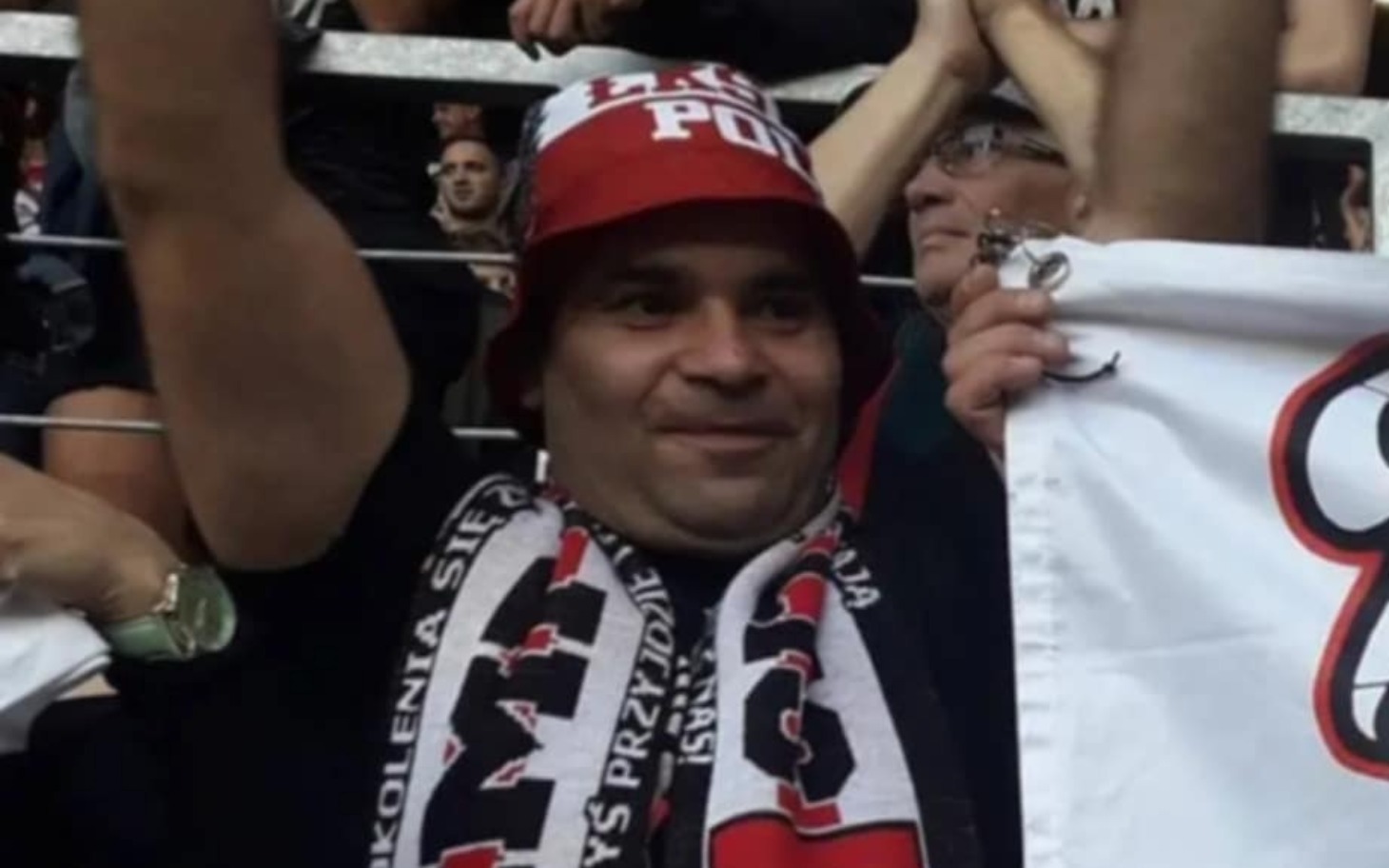 
        Mężczyzna w czapce kibica, radośnie wspierający swoją drużynę.
    