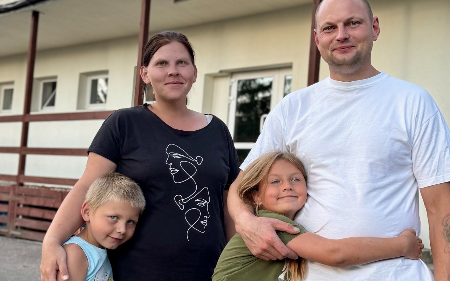 
        Rodzina pozująca przed budynkiem, z dziećmi.
    