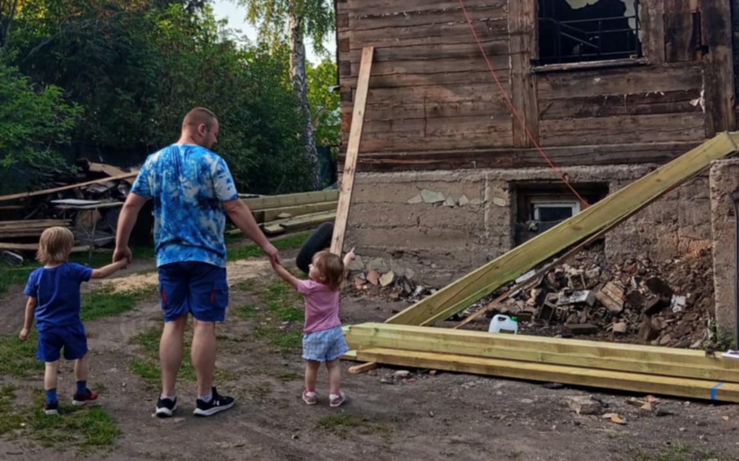 
        Rodzina spacerująca obok zniszczonego budynku.
    