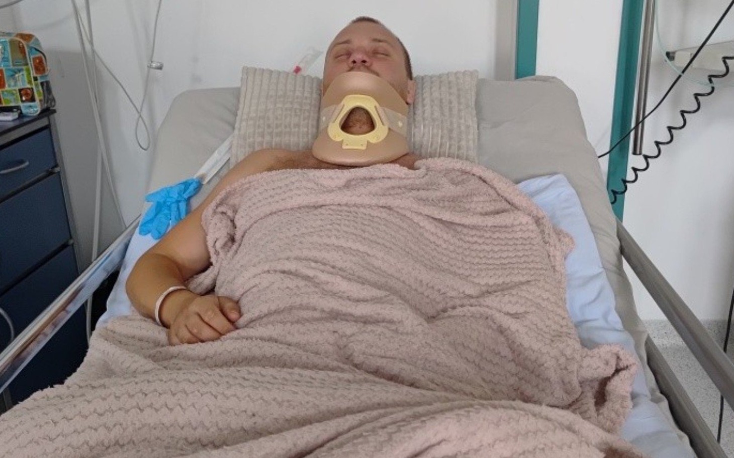 
        Mężczyzna leżący w szpitalnym łóżku, w trakcie rehabilitacji.
    