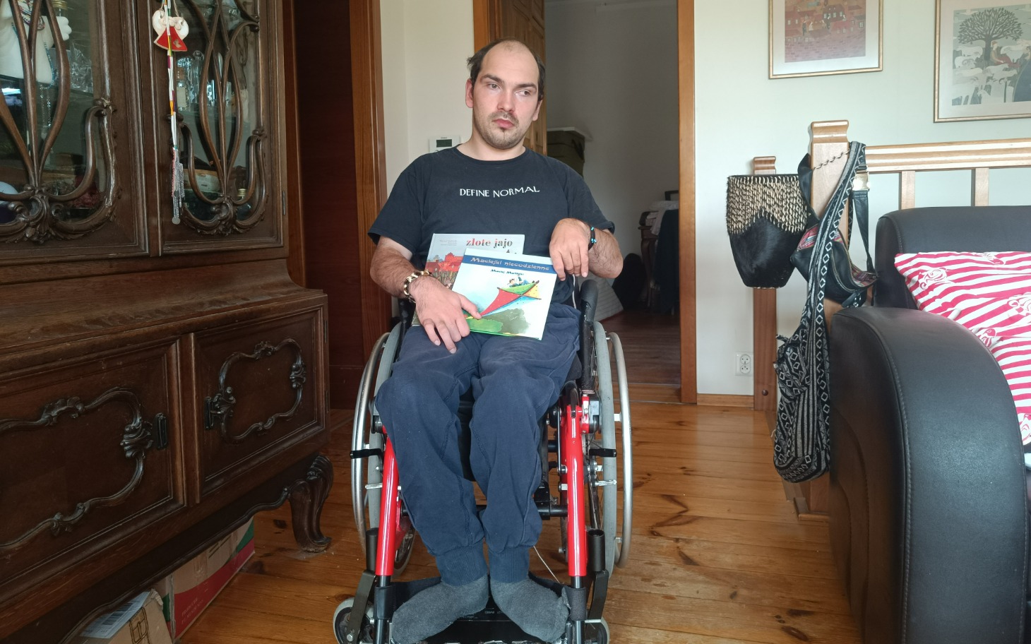 
        Mężczyzna na wózku inwalidzkim trzymający rysunek.
    