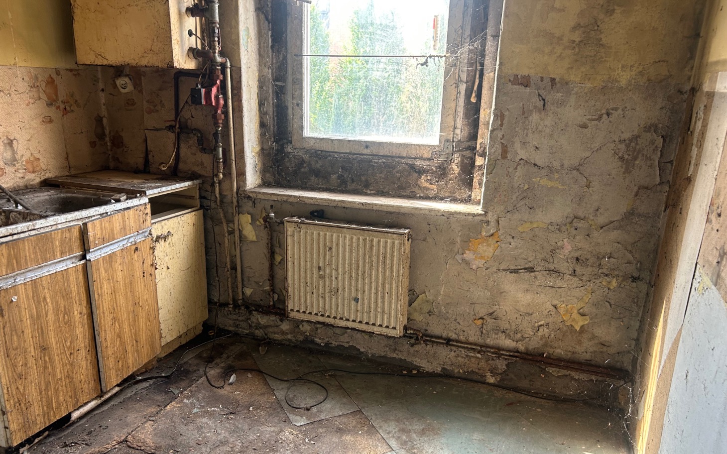 
        Zniszczona kuchnia z widokiem na okno.
    