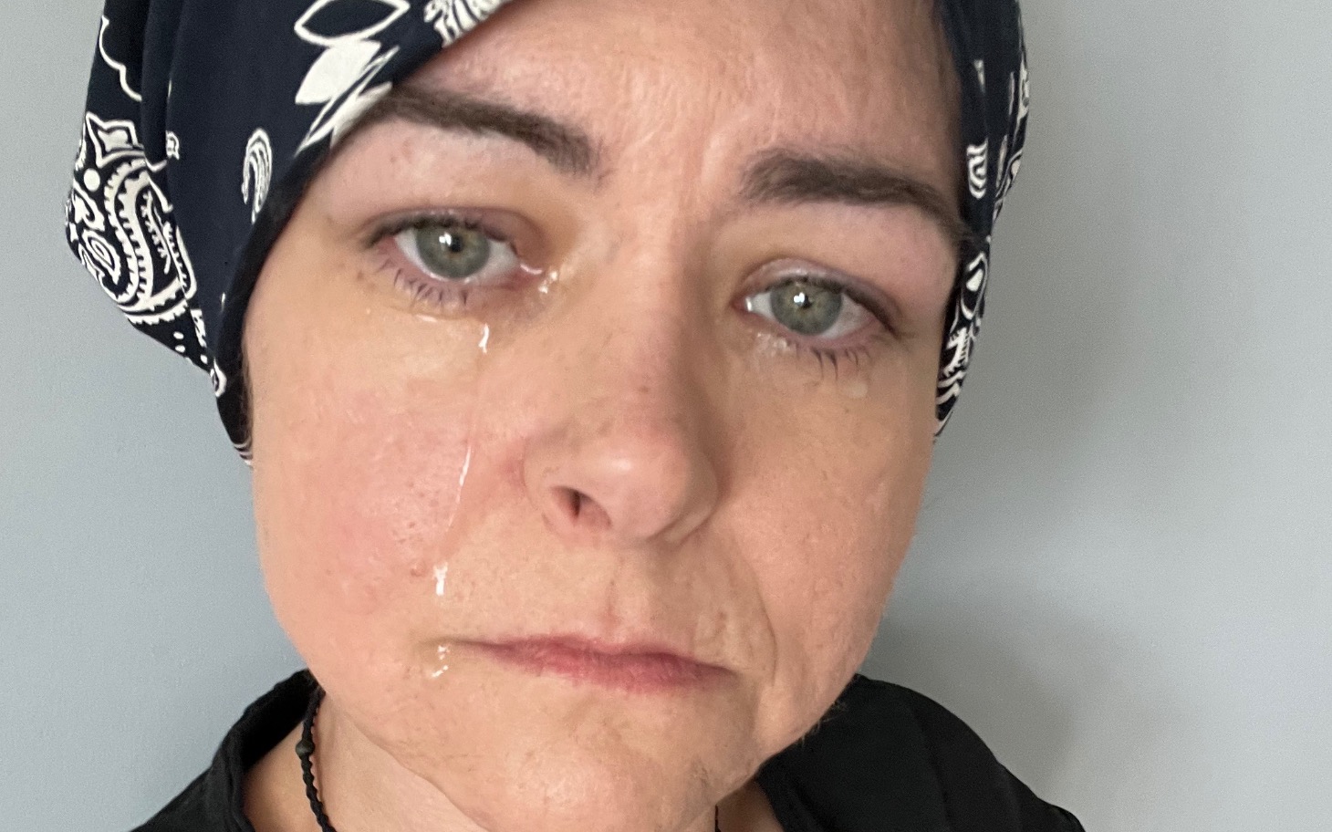 
        Kobieta w chustce, z wyraźnym smutkiem na twarzy.
    