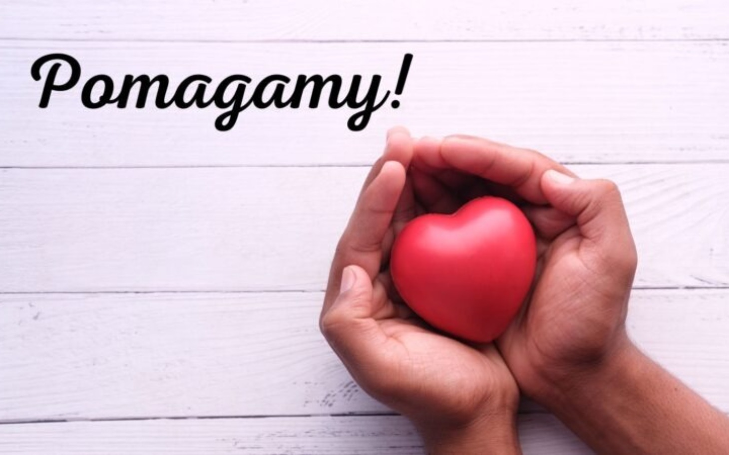 
        Ręce trzymające czerwone serce na tle drewnianym.
    