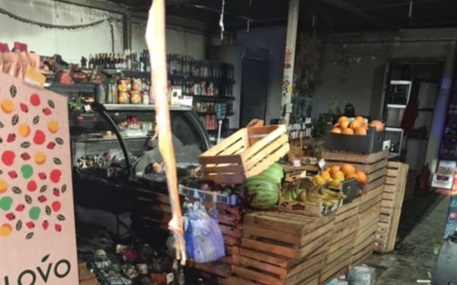 
        Zniszczony sklep spożywczy po pożarze, z towarami na podłodze.
    