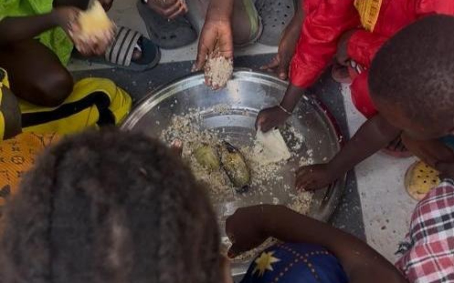 
        Dzieci jedzące wspólnie posiłek z dużej miski.
    