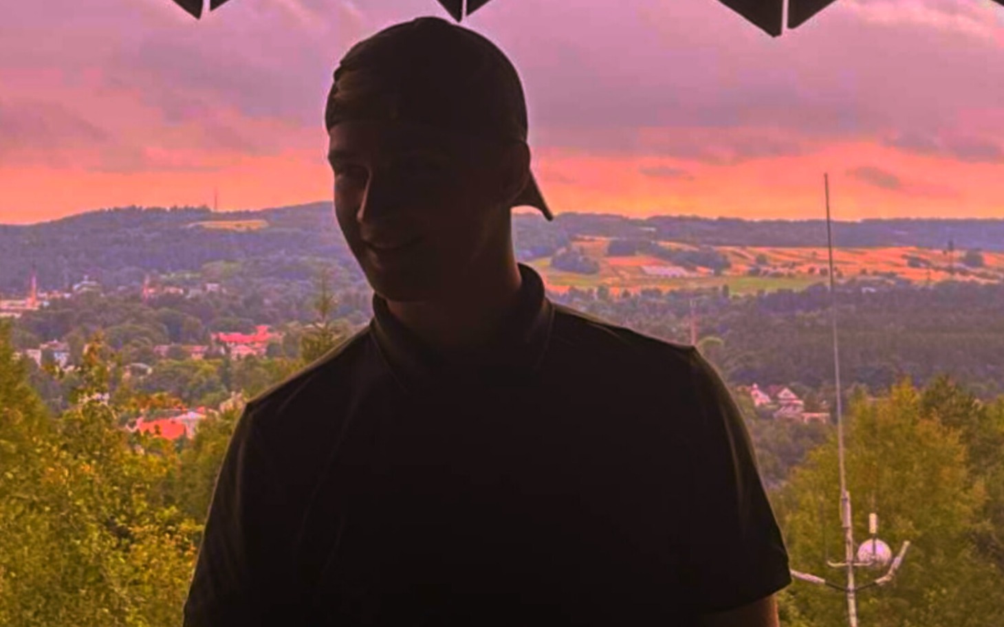 
        Człowiek w cieniu, z widokiem na krajobraz.
    