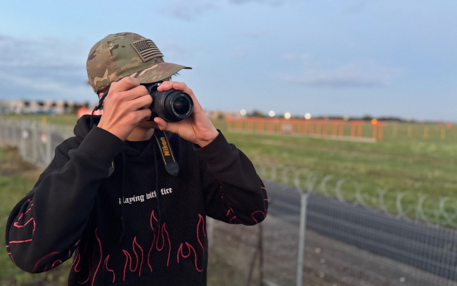 
        Młody fotograf z aparatem na tle krajobrazu.
    
