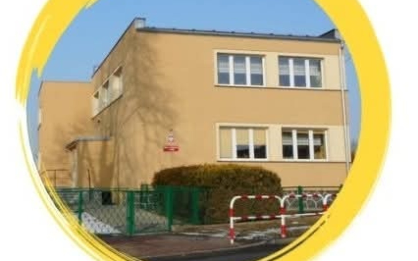 
        Budynek z żółtą elewacją i zielonym ogrodzeniem.
    