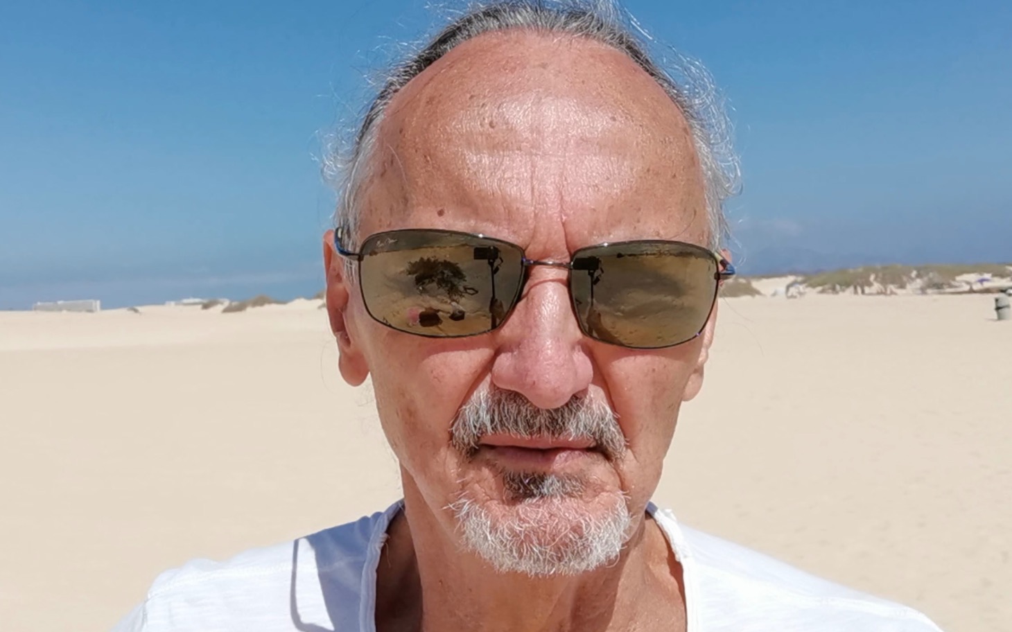 
        Mężczyzna w okularach przeciwsłonecznych na plaży.
    