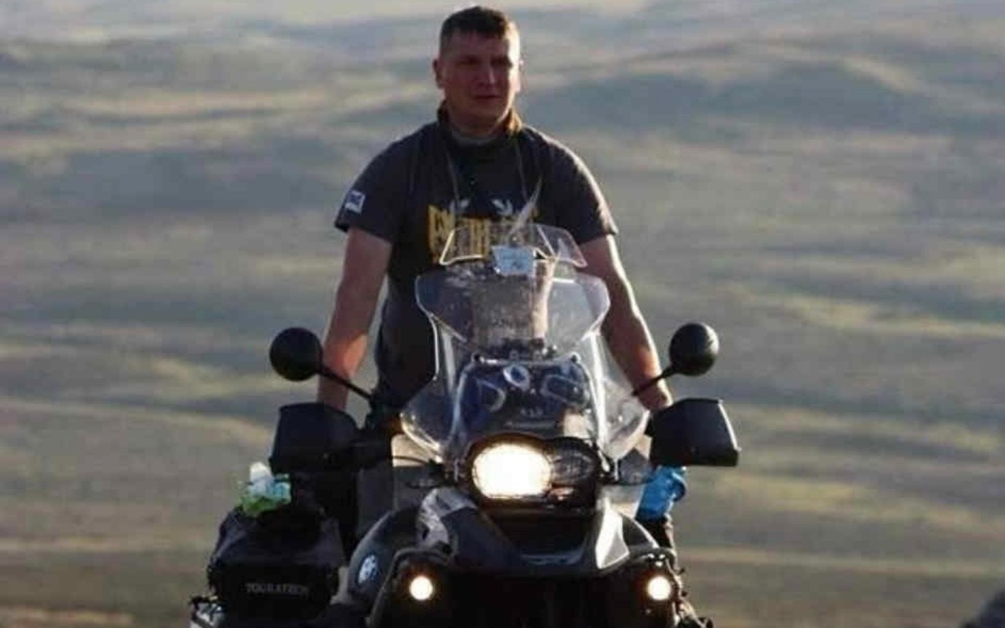 
        Mężczyzna na motocyklu w otoczeniu gór.
    