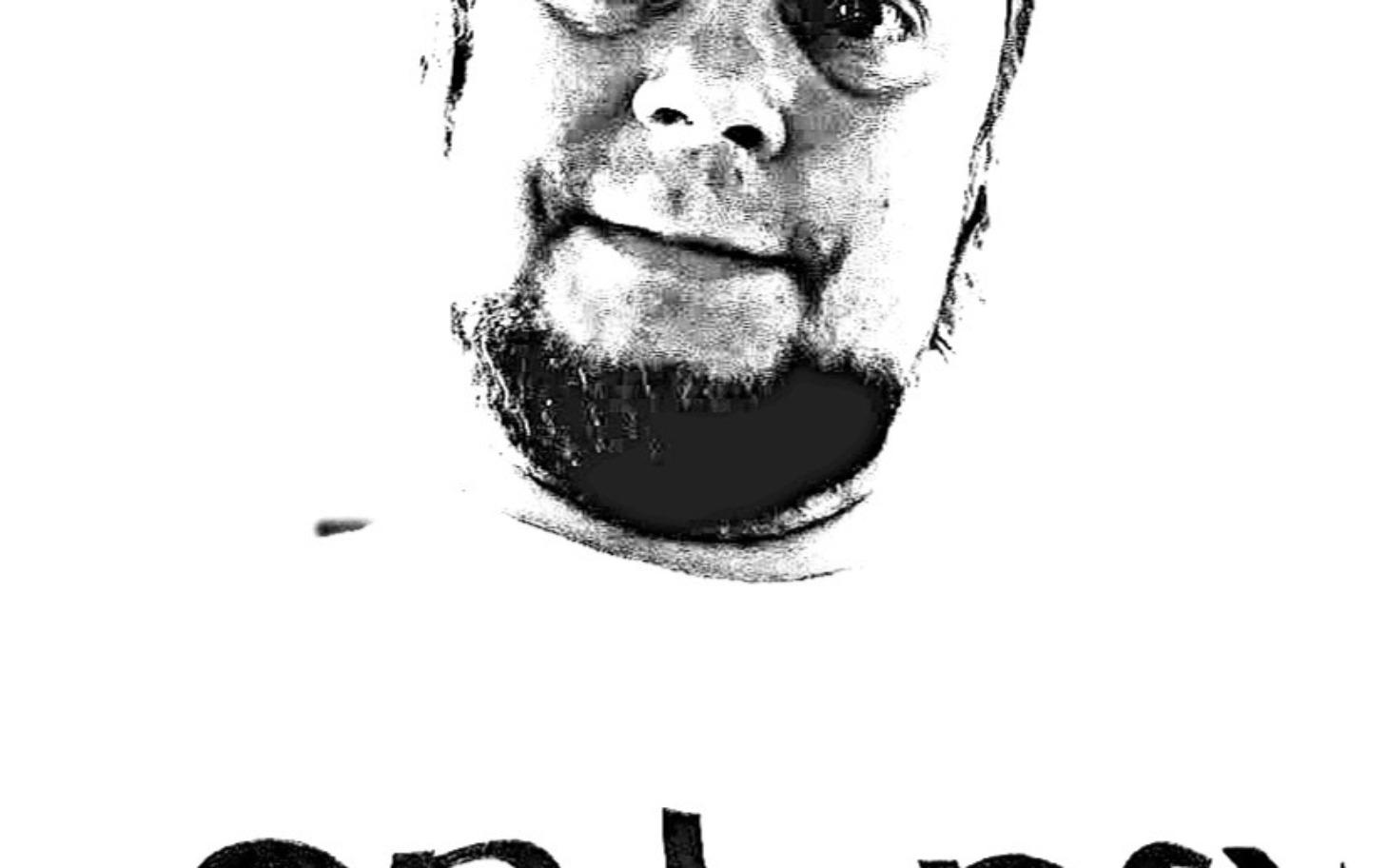 
        Czarno-białe selfie mężczyzny z brodą, w t-shircie z napisem.
    