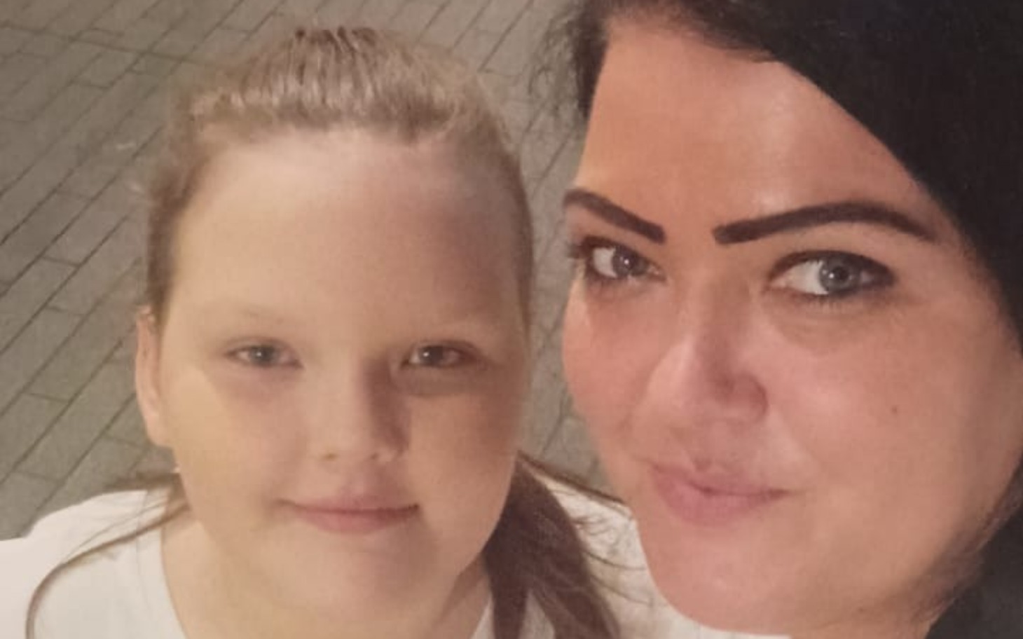 Dwie kobiety, jedna z nich z dzieckiem, obie uśmiechnięte.