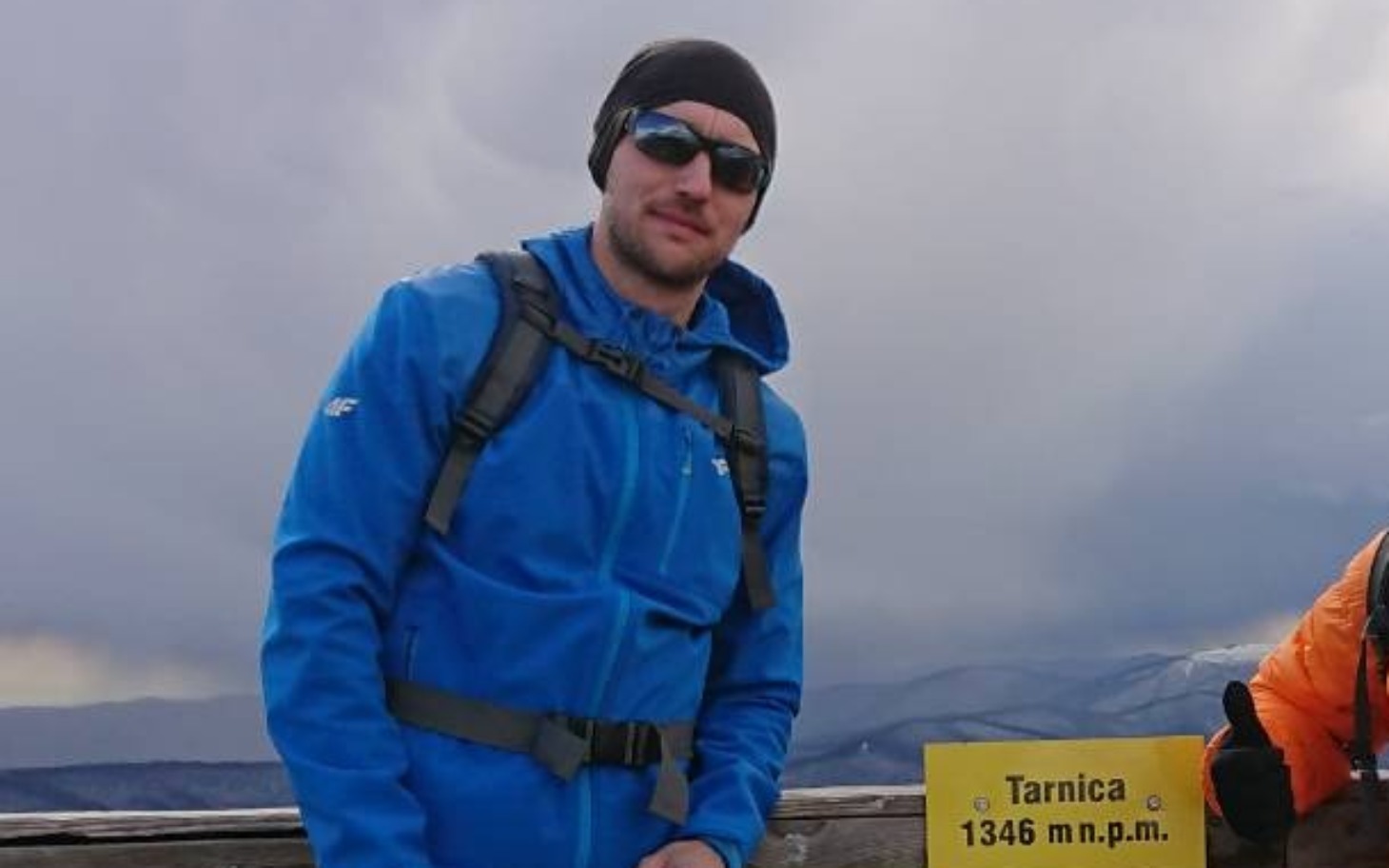 
        Mężczyzna na szczycie Tarnicy z tabliczką.
    